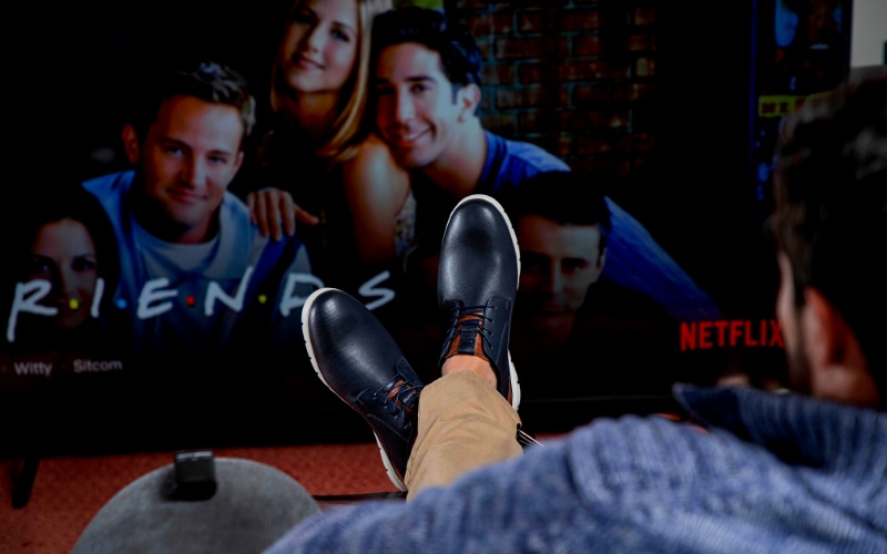 Hombre viendo television con sus zapatos de cuero